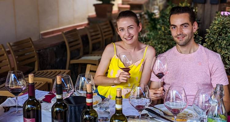 Stel geniet van wijnproeverij aan een tafel met veel flessen.