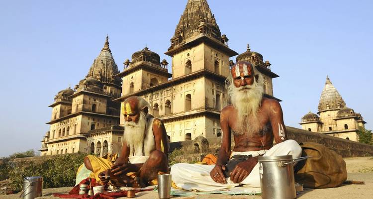 Twee oudere mannen zittend voor een historische tempel.