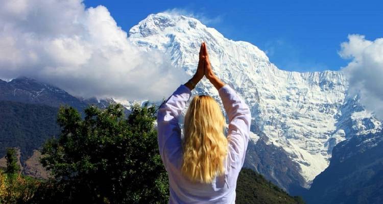 Person practicing yoga with a snow-capped mountain background.