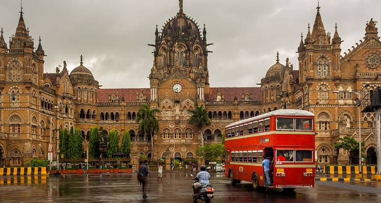 Architektonisches Wunderwerk Chhatrapati Shivaji Terminus mit einem roten Bus.