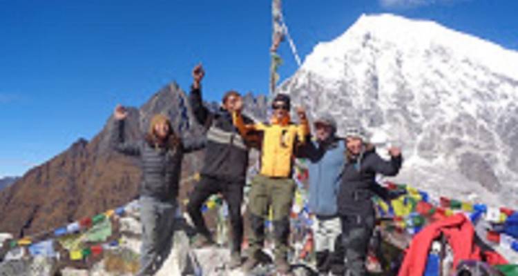Groep mensen die feest vieren op een bergtop met gebedsvlaggen.