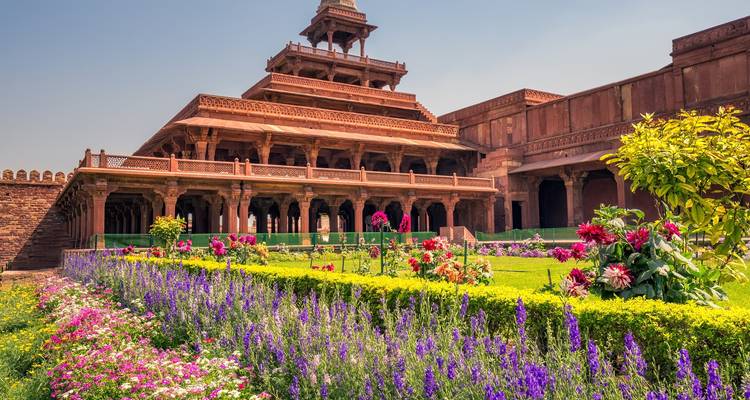 Paleisarchitectuur met kleurrijke tuin ervoor.