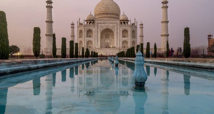 Das ikonische Taj Mahal spiegelt sich bei Sonnenuntergang in einem Wasserbecken wider.