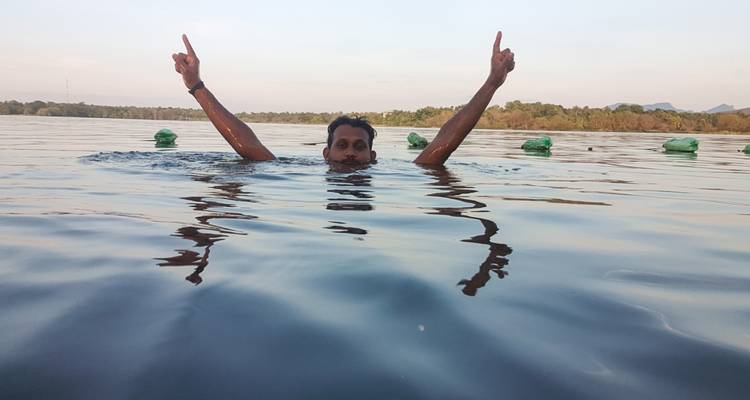 Un homme nageant les mains levées dans un lac.