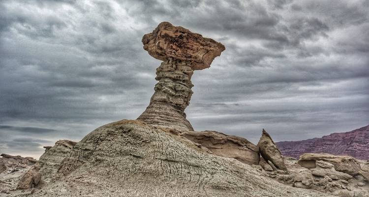 Tall rock formations resembling a mushroom under a cloudy sky.