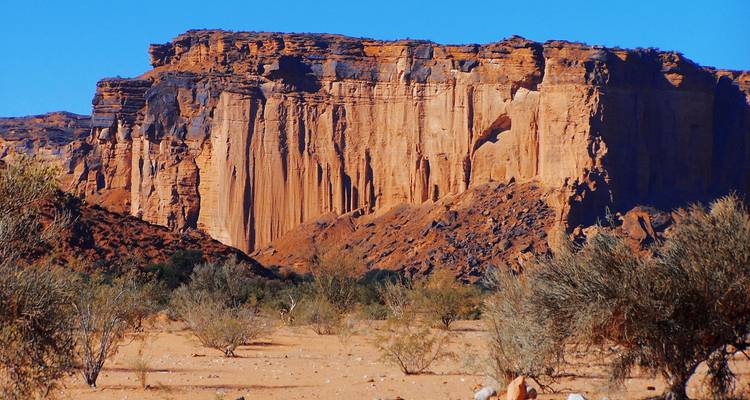 Expansive view of rugged red rock cliffs in a desert landscape.