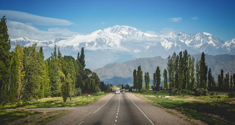 Long road leading to snow-capped mountains.
