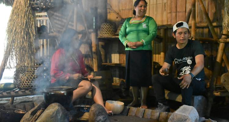 Los miembros de la comunidad se reunieron alrededor de un hogar humeante discutiendo las tradiciones locales dentro de una choza.