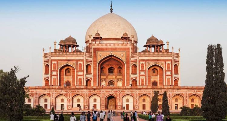 Mausoleum met een grote koepel en ingewikkelde details, omringd door weelderige tuinen.