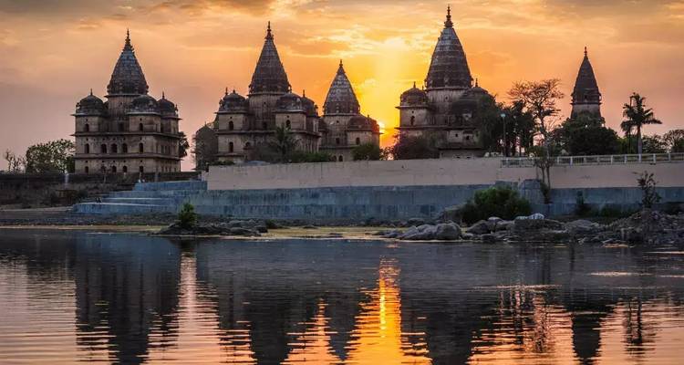 Verzierter Tempel mit Türmen, die sich bei Sonnenuntergang im Wasser spiegeln.