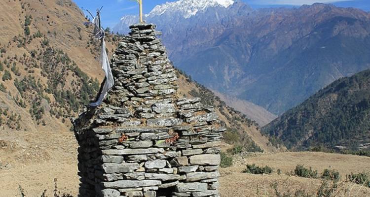 Een kleine stenen structuur met bergen op de achtergrond.