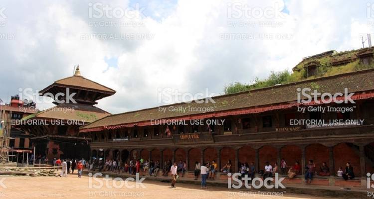 Ein öffentlicher Platz mit Menschen, die sitzen und umhergehen. Das Bild enthält Wasserzeichen.