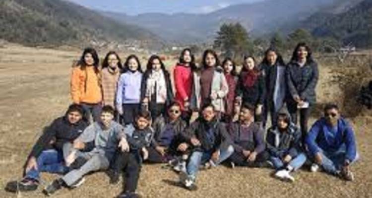 Ein Gruppenfoto von Personen, die in einem Feld posieren, mit Bergen im Hintergrund.