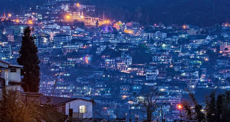 Eine atemberaubende abendliche Stadtlandschaft mit Lichtern, die den Hügel beleuchten.