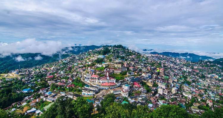 Ein Panoramablick auf eine Hügelstadt mit bunten Gebäuden und üppigem Grün.
