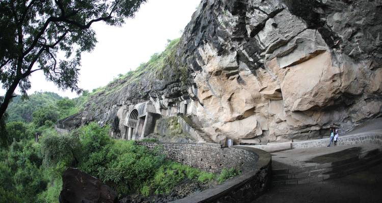 Façade rocheuse des grottes d'Ajanta avec une végétation luxuriante.