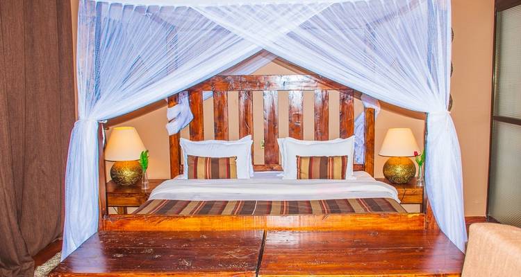 Comfortable bed with mosquito nets inside a cozy room.