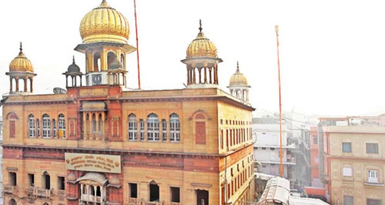 Ein Sikh-Tempel mit goldenen Kuppeln vor einem hellen Himmel.