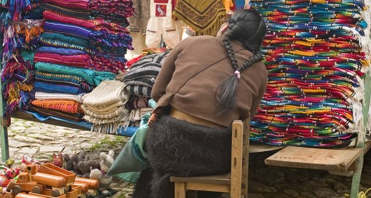 A woman working with colorful textiles at an outdoor market.