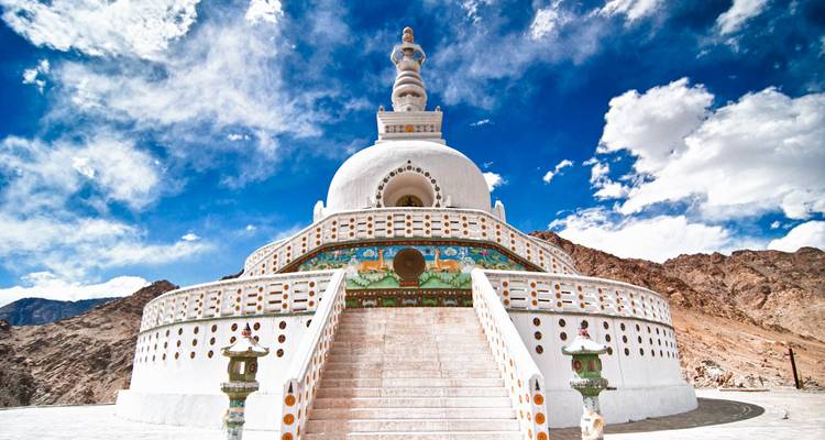 Strahlend weiße Shanti Stupa vor einem leuchtend blauen Himmel und felsigen Hügeln.