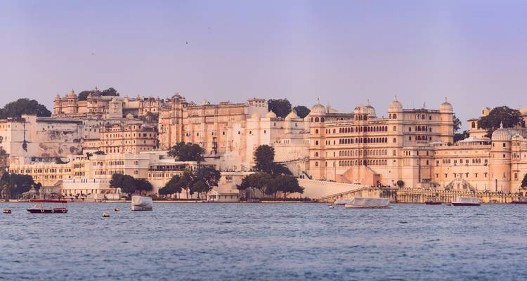 Large white palace on a lake with clear skies.
