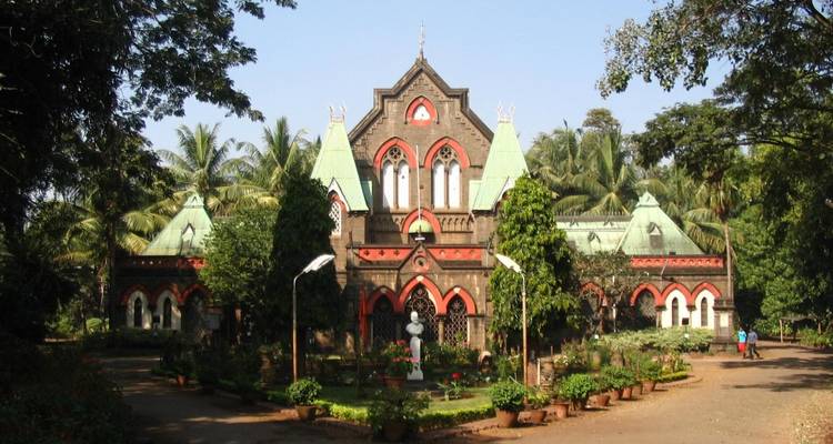 Ein gotisches Gebäude mit gewölbten Fenstern und üppiger Vegetation.
