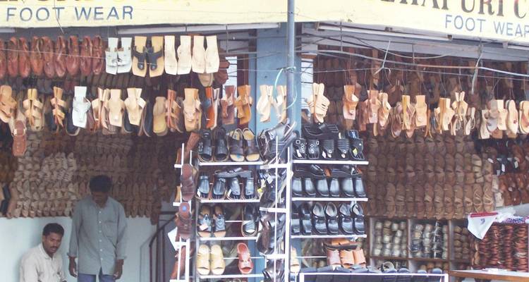 Ein Straßenhändler, der handgefertigte Schuhe verkauft, die auf Gestellen ausgestellt sind.