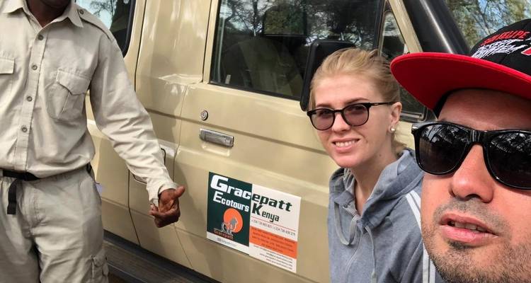 Drie mensen voor een safariauto met een logo.