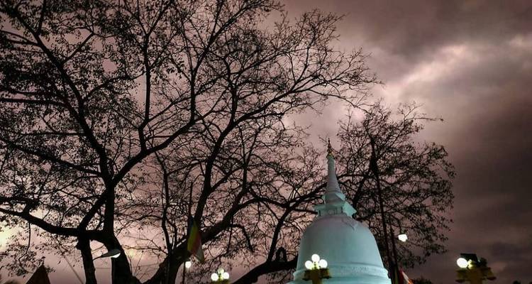 Weiße Stupa unter einem dramatischen bewölkten Himmel.