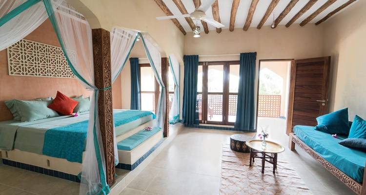 Habitación de hotel espaciosa y elegantemente decorada con cama con dosel y ventanas con vista al jardín.