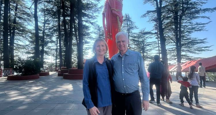 Couple posing in a park with tall trees.