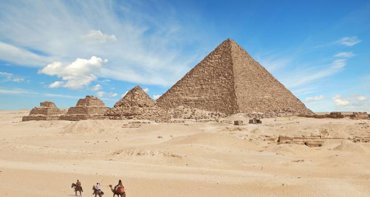 Een persoon met een rugzak staat met het gezicht naar een bergachtig landschap onder een bewolkte hemel.