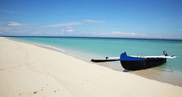 Une plage paisible avec un canoë à balancier traditionnel sur le rivage.