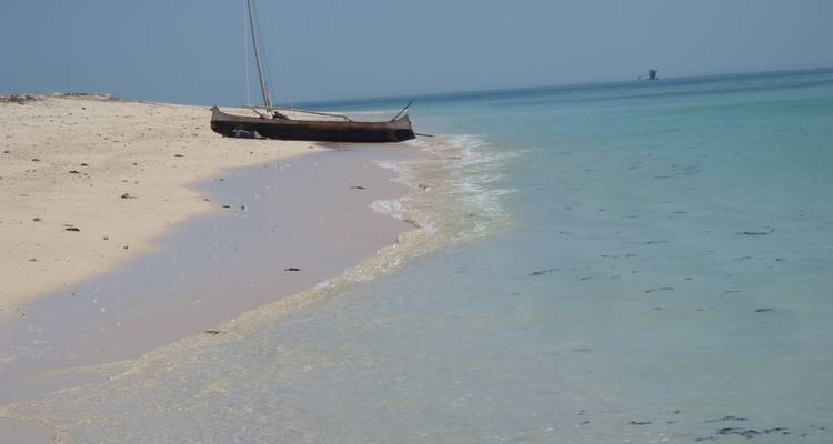 Un petit bateau sur une plage de sable calme.