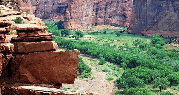 Felsige Klippe mit einem grünen Tal darunter.