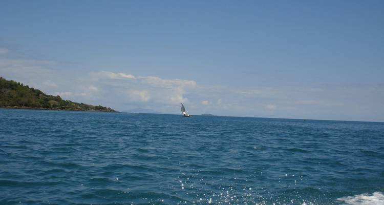 Open sea with a small sailboat in the distance.