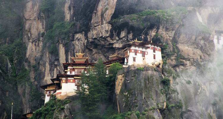 Iconisch Taktsang Klooster neergestreken op een rotswand in een mistige omgeving.