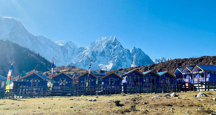 Refugios de montaña coloridos con picos nevados al fondo.