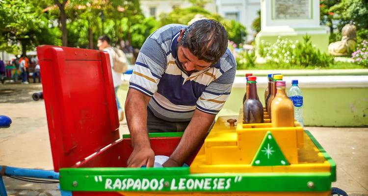 Un hombre preparando un postre tradicional desde un carrito colorido.