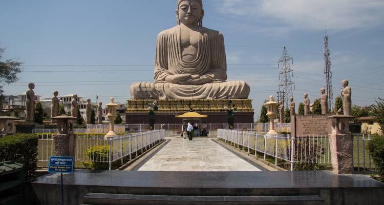 Grande statue de Bouddha assis avec de petits visiteurs s'approchant sur un chemin de pierre, journée ensoleillée et lumineuse