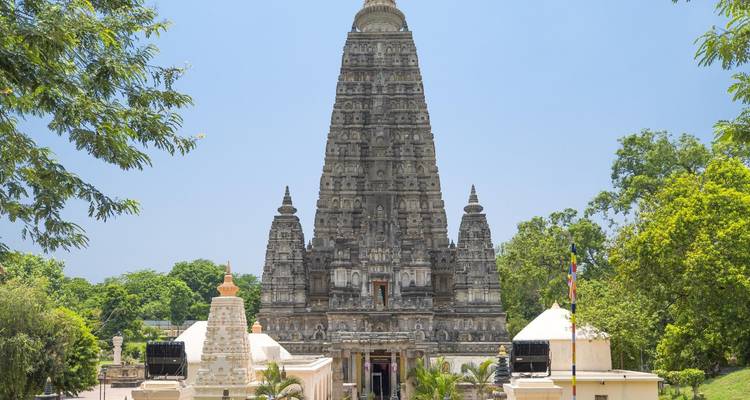 Vue de face du temple Mahabodhi orné encadré par la verdure sous un ciel dégagé