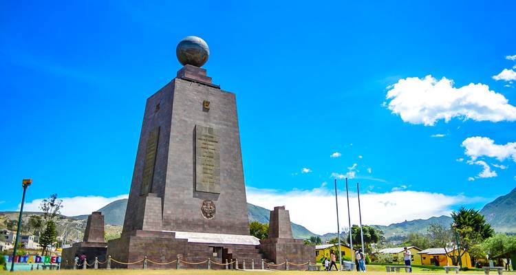 Groot monument met een wereldbol bovenop onder een heldere blauwe hemel.