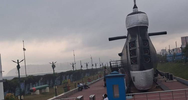 Vue de côté d'un sous-marin exposé sous un ciel gris avec une côte brumeuse au-delà