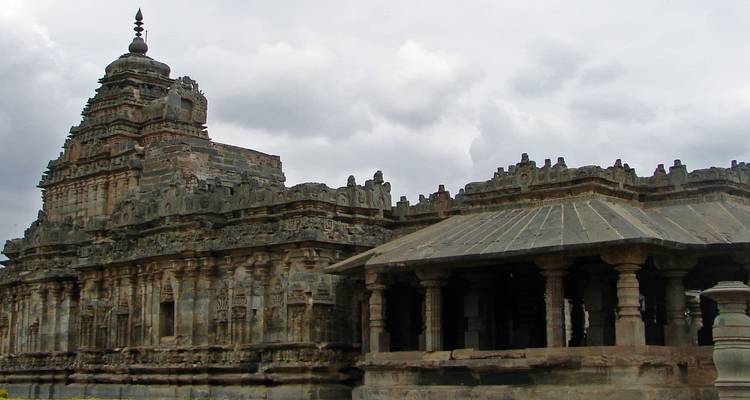 Temple en pierre ornementé avec un ciel nuageux en arrière-plan.