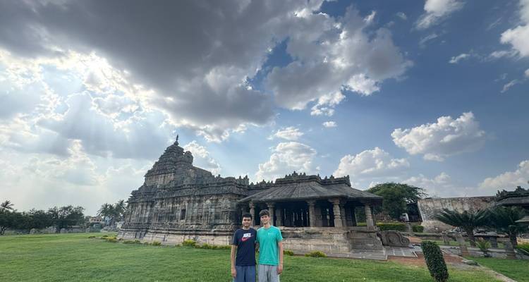 Deux personnes debout devant un temple avec un ciel dramatique.