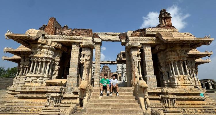 Ruines d'un temple en pierre avec des motifs complexes et des personnes assises.