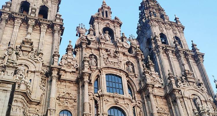 Detalladas tallas de piedra y torres que se alzan de la Catedral de Santiago de Compostela contra un cielo azul despejado.