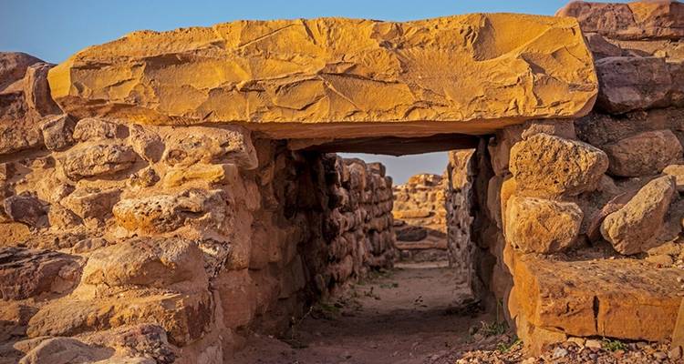 Stenen ruïnes met een smalle doorgang onder een grote plaat.