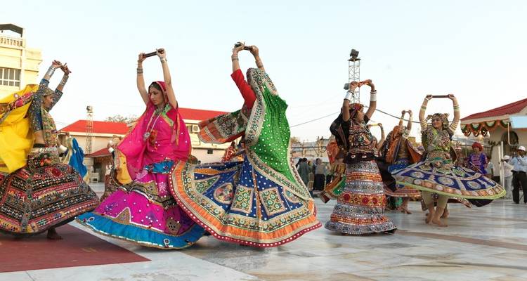 Gruppe von Frauen in bunten traditionellen Kleidern, die einen Tanz aufführen.