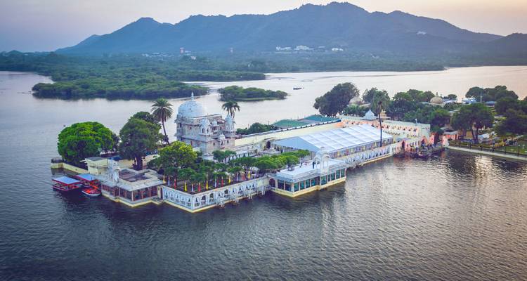 Inseltemplelanlag auf einem See mit Bergen im Hintergrund.